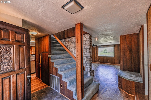 77993 Point Adams Rd, Clatskanie, OR 97016 - staircase featuring a textured ceiling, wooden walls, and wood finished floors