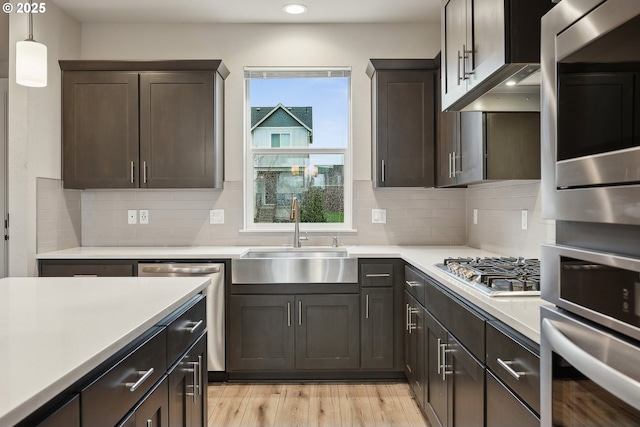 kitchen with light countertops, light wood-type flooring, stainless steel appliances, and a sink