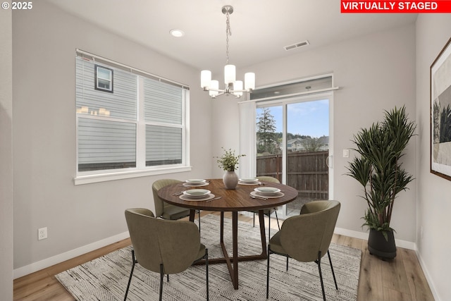 dining space featuring visible vents, baseboards, an inviting chandelier, and light wood-style flooring