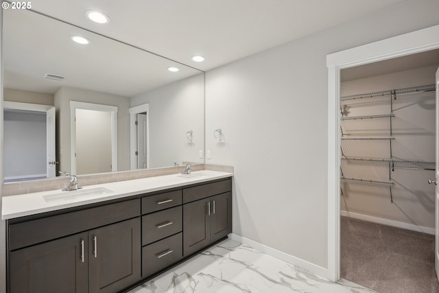 full bathroom with a sink, a walk in closet, and marble finish floor