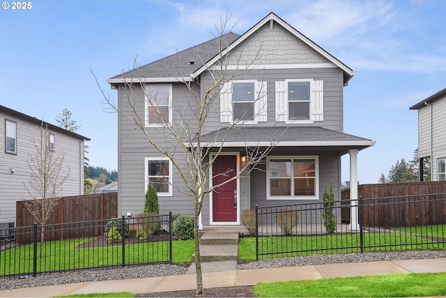 view of front facade with a fenced front yard, roof with shingles, a porch, and a front lawn