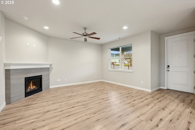 unfurnished living room featuring wood finished floors, recessed lighting, baseboards, and a tile fireplace