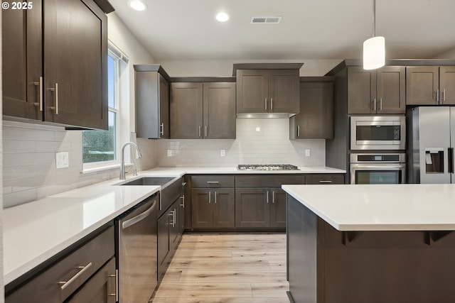 kitchen with visible vents, dark brown cabinetry, light countertops, stainless steel appliances, and a sink