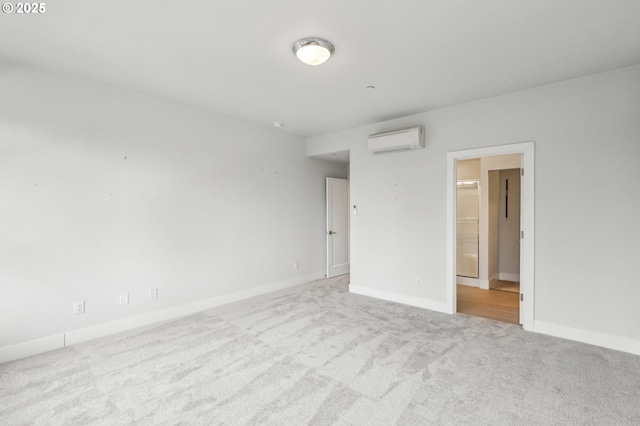 spare room featuring a wall mounted AC, carpet, and baseboards