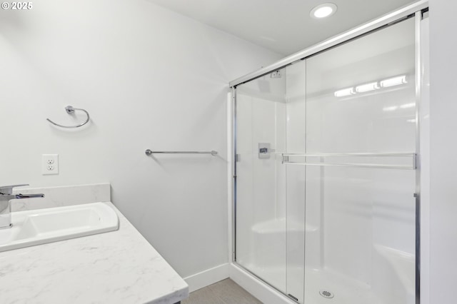 full bathroom featuring a stall shower, vanity, and baseboards