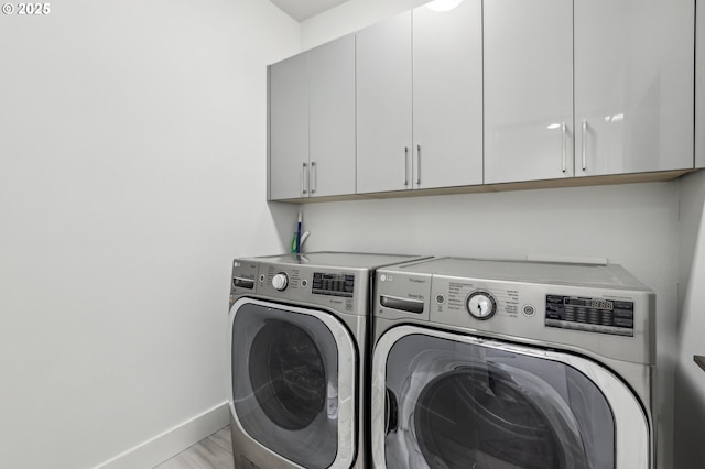 washroom featuring cabinet space, washer and dryer, and baseboards