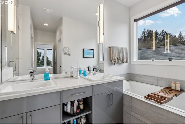 bathroom with double vanity, a sink, a bath, and a shower stall