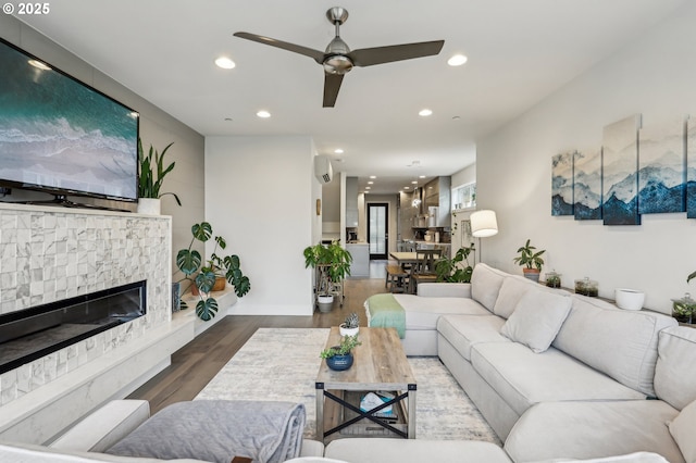 living room featuring recessed lighting, a wall mounted AC, a ceiling fan, a stone fireplace, and wood finished floors