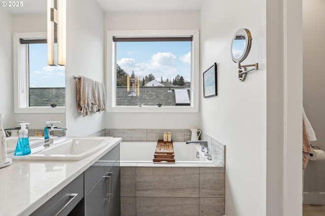 full bath with plenty of natural light, vanity, and a bath