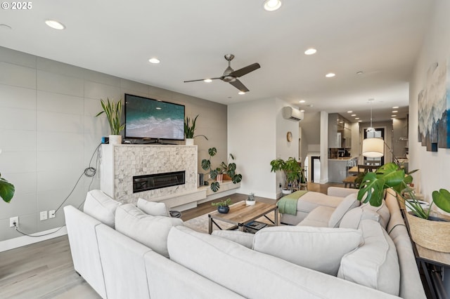 living area with an AC wall unit, wood finished floors, a high end fireplace, and recessed lighting