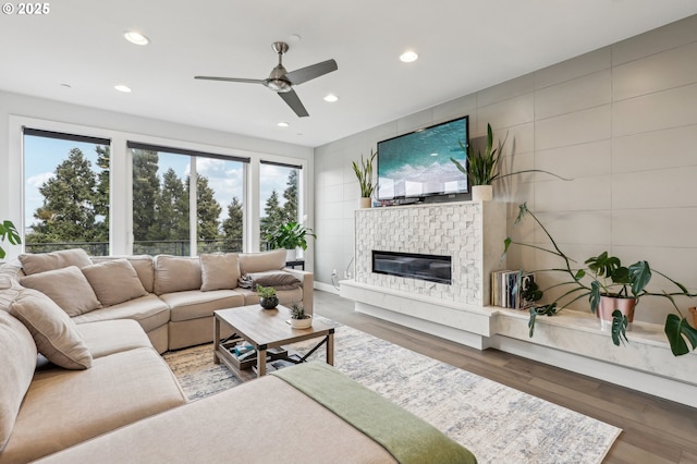 living room with a fireplace, a ceiling fan, wood finished floors, and recessed lighting