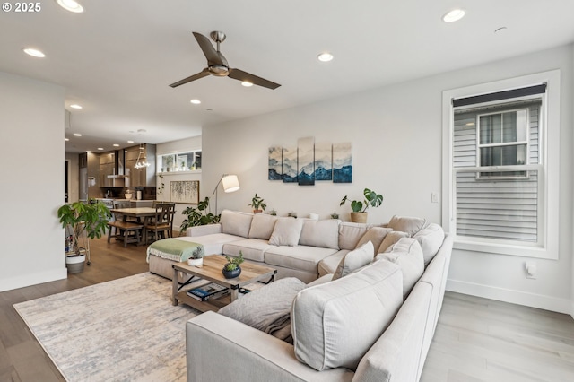 living room with recessed lighting, a ceiling fan, light wood-style flooring, and baseboards