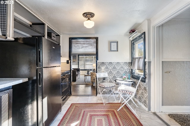 kitchen featuring black fridge and a textured ceiling