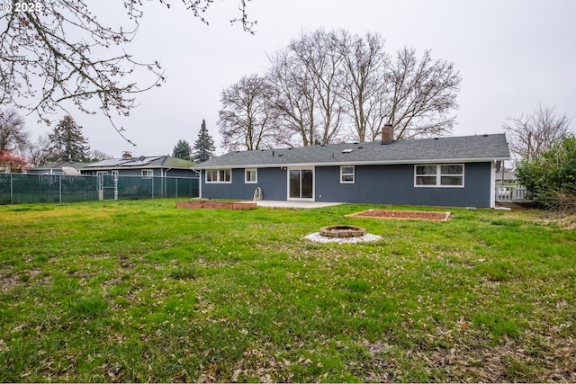 rear view of house with a yard, a patio, and a fire pit