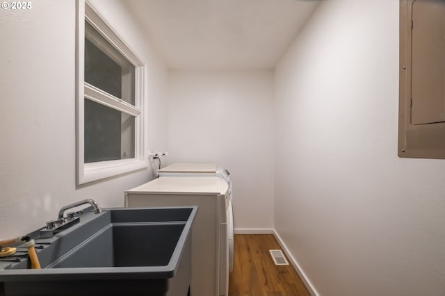 laundry room featuring hardwood / wood-style flooring, sink, electric panel, and washing machine and dryer