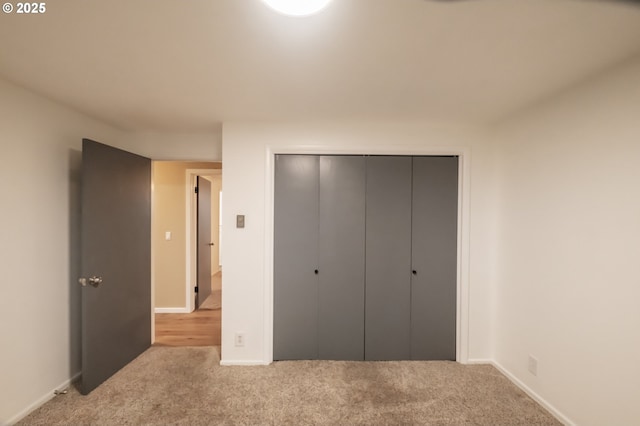 unfurnished bedroom with light colored carpet and a closet