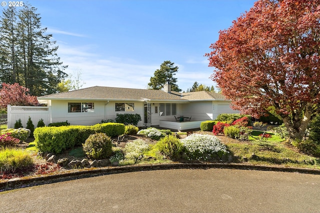 ranch-style home featuring fence, an attached garage, a chimney, and a shingled roof