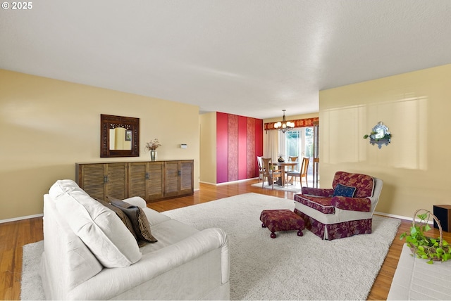 living area featuring baseboards, wood finished floors, and a notable chandelier