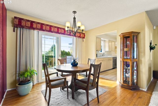dining room with light wood-type flooring, a textured ceiling, and a chandelier