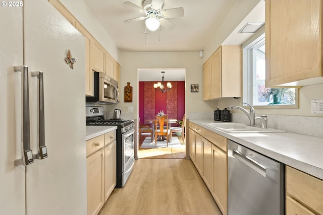 kitchen featuring light brown cabinetry, a sink, light wood-style floors, light countertops, and stainless steel appliances