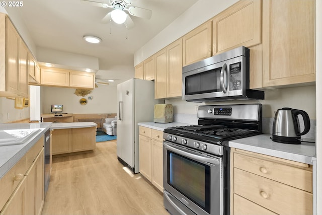 kitchen with light countertops, appliances with stainless steel finishes, light brown cabinets, and a ceiling fan