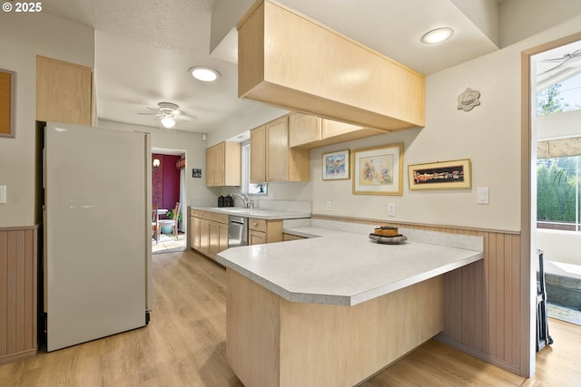 kitchen with freestanding refrigerator, wainscoting, a peninsula, light brown cabinets, and light countertops