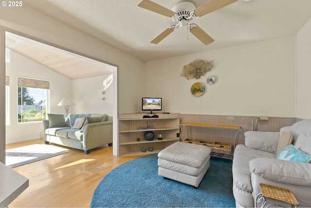 living area with a ceiling fan, wood finished floors, and lofted ceiling
