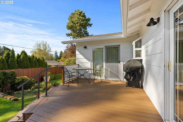 wooden terrace featuring grilling area, outdoor dining area, and a fenced backyard