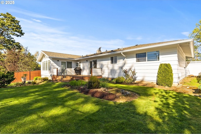 back of property with a yard, fence, and a wooden deck