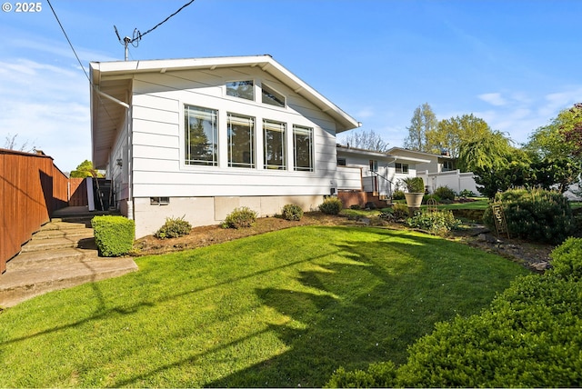 back of house with a lawn, crawl space, and fence