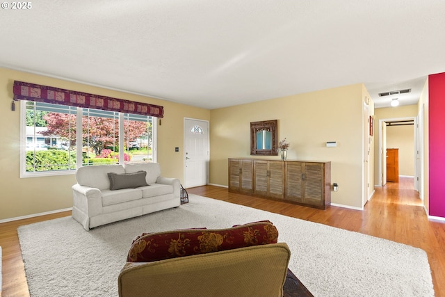 living area featuring baseboards, visible vents, and wood finished floors