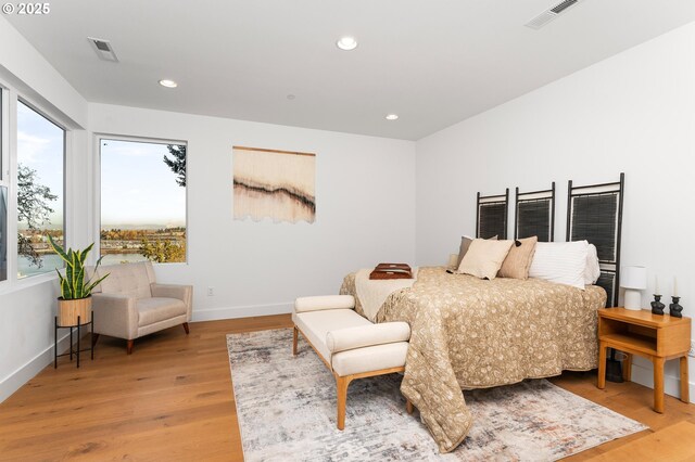 bedroom featuring baseboards, multiple windows, light wood-type flooring, and visible vents