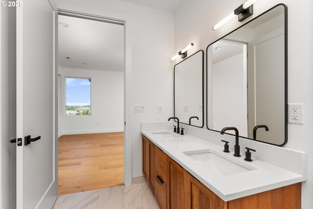 bathroom featuring a sink, baseboards, double vanity, and marble finish floor