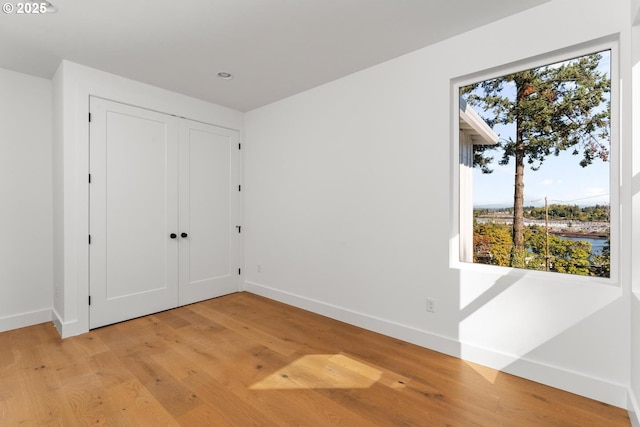 unfurnished bedroom featuring a closet, baseboards, recessed lighting, and light wood-type flooring