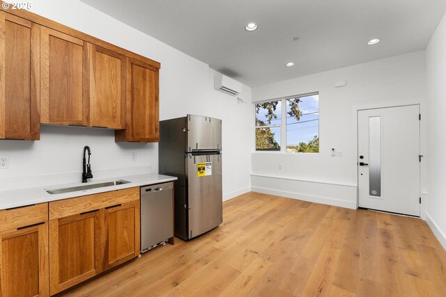 kitchen featuring a sink, appliances with stainless steel finishes, a wall mounted AC, and brown cabinets