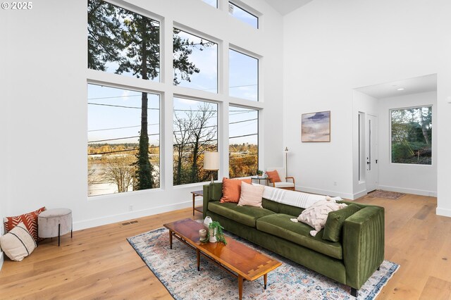 living area featuring baseboards, visible vents, wood finished floors, and a towering ceiling