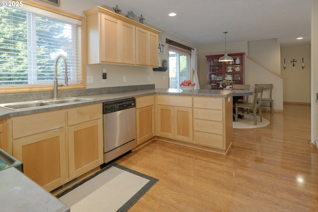 kitchen featuring light brown cabinets, a sink, a peninsula, light wood finished floors, and dishwasher