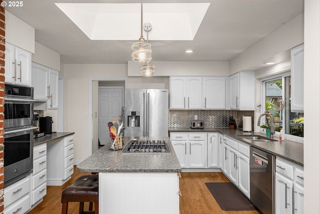 20060 SW Clarion St, Beaverton, OR 97003 - kitchen featuring appliances with stainless steel finishes, decorative backsplash, a skylight, white cabinets, and recessed lighting