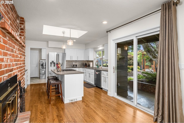 20060 SW Clarion St, Beaverton, OR 97003 - kitchen with stainless steel appliances, a skylight, a fireplace, washer / clothes dryer, and a center island