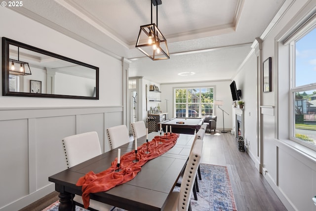 3753 NW Talamore Ter, Portland, OR 97229 - dining room with a tray ceiling, a decorative wall, wood finished floors, a fireplace, and ornamental molding