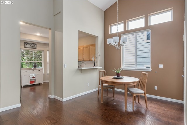 dining room with baseboards, a notable chandelier, dark wood finished floors, and a towering ceiling