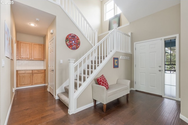 stairs featuring baseboards, wood finished floors, and a towering ceiling