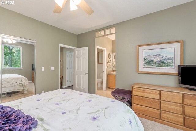bedroom with connected bathroom, ceiling fan, and light carpet