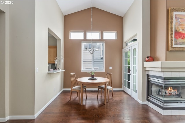 dining room featuring a tiled fireplace, wood finished floors, baseboards, and a chandelier