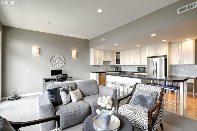 living area with light wood-type flooring, recessed lighting, visible vents, and baseboards