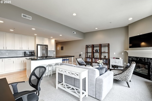 living room featuring a fireplace, visible vents, and recessed lighting