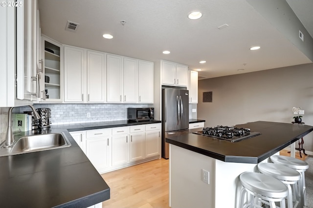 kitchen featuring stainless steel appliances, dark countertops, visible vents, and a sink