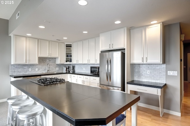 kitchen featuring visible vents, dark countertops, stainless steel appliances, white cabinetry, and a sink