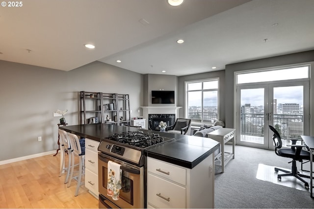 kitchen featuring french doors, dark countertops, a premium fireplace, stainless steel range with gas stovetop, and white cabinets