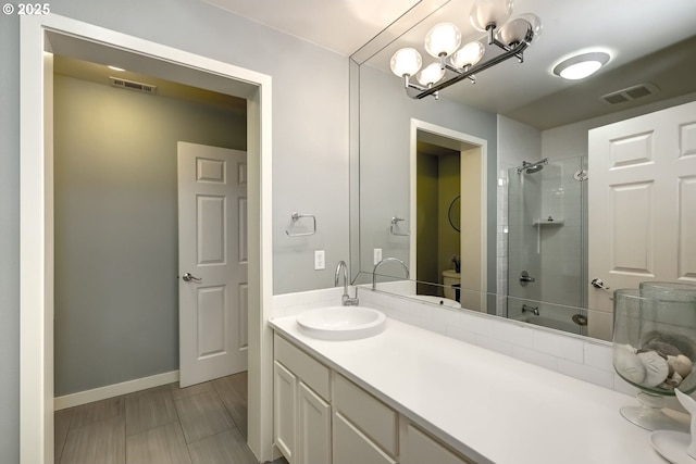 bathroom featuring toilet, visible vents, tiled shower, and vanity